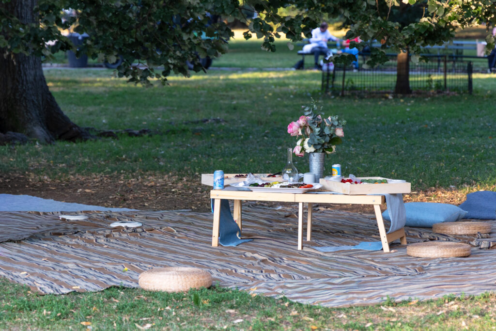 Photograph of a picnic table set with flowers and food in Central Park, captured by Pamela Thomas-Graham, evoking New York warmth and style.