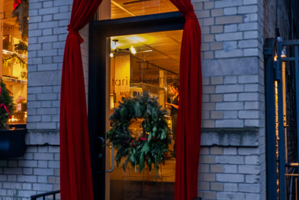 West Village boutique window with wreath and warm interior lighting during the holiday season, photographed by Pamela Thomas-Graham.