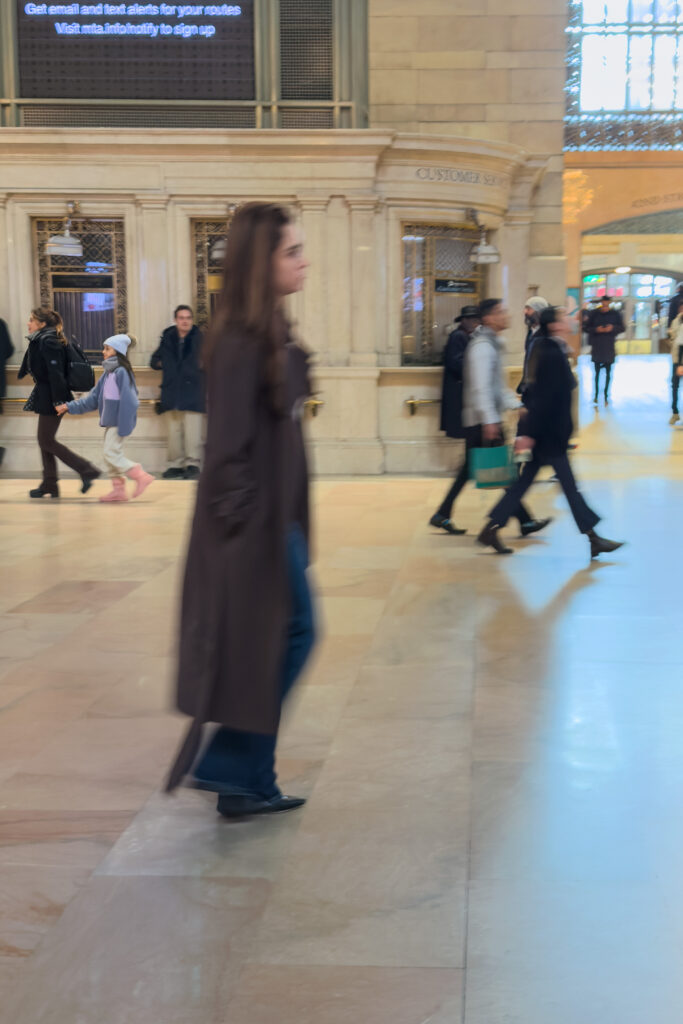 Woman moving through Grand Central Terminal in New York, dressed in relaxed yet authoritative power casual clothing.