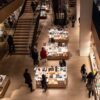 Best museum shops worldwide: overhead view of a modern museum store interior with curated design objects, books, and visitors browsing.