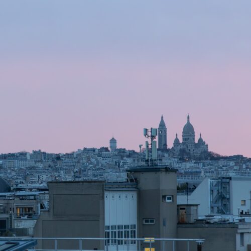 Carry-On Couture spring city packing list — Paris skyline at dusk in late March 2026 (Sacre-Coeur), spring travel capsule wardrobe.