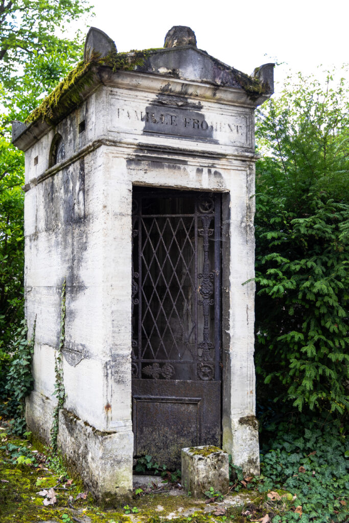 Small tomb-house with an open iron door at Père Lachaise Cemetery in Paris.
