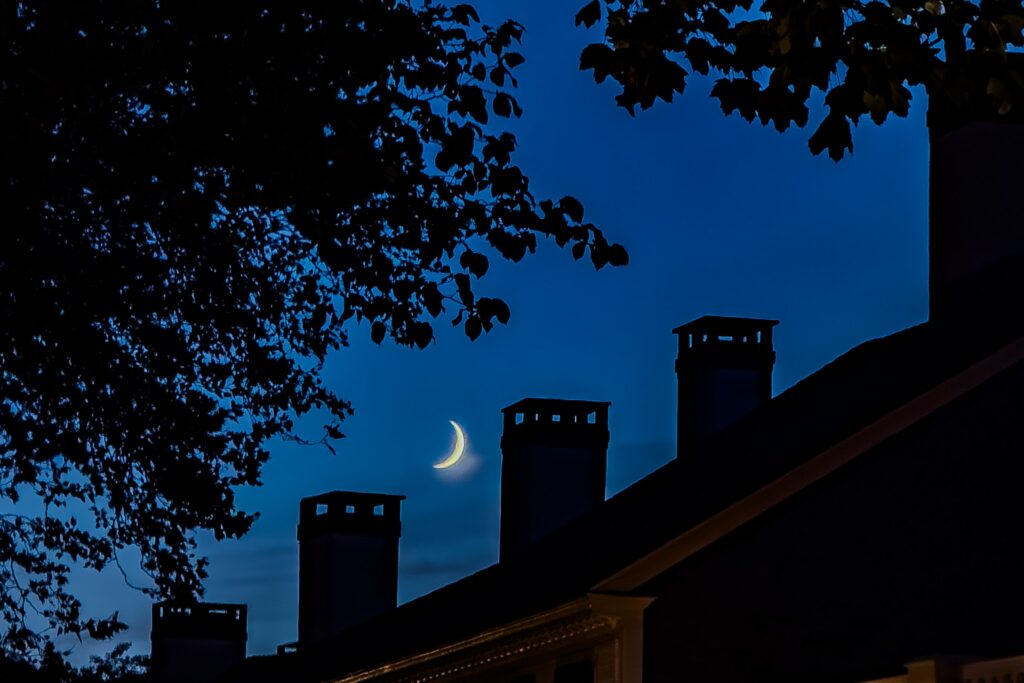 Crescent moon over Vineyard rooftops at blue hour in Edgartown on Martha’s Vineyard.