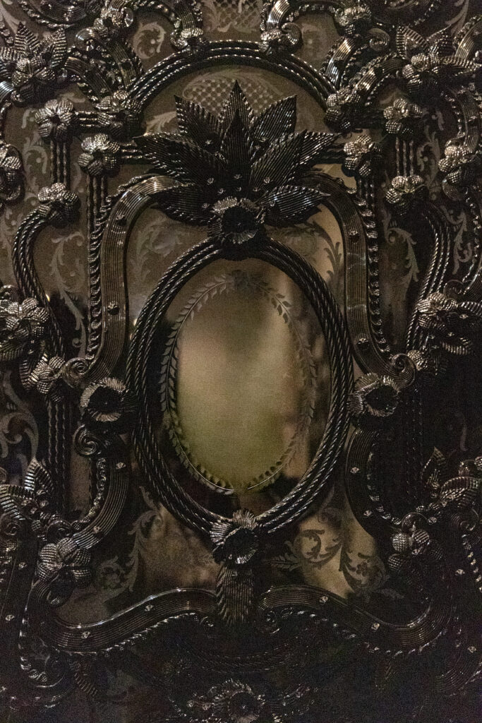 Detail of Fred Wilson’s Iago’s Mirror showing layered black Murano glass, ornament, and reflective surfaces.