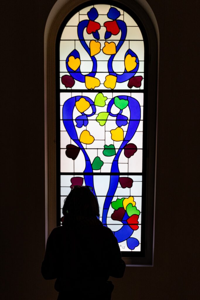 Visitor silhouetted before Henri Matisse stained-glass design from the Chapelle du Rosaire at a Paris exhibition.