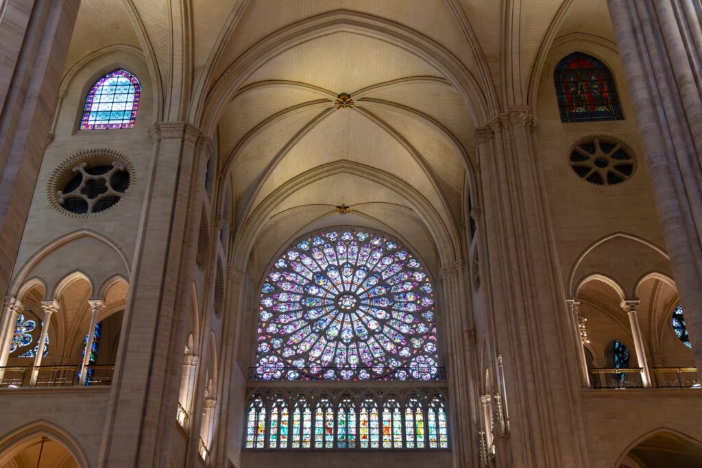 Restored interior of Notre-Dame Cathedral in Paris with rose window, stained glass and vaulted nave.
