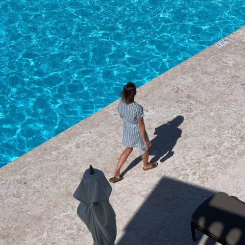Woman walking beside a hotel pool in Bermuda, illustrating warm weather business travel style and professional boundaries in a resort setting.
