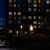 Oversized candle sculptures glowing on the High Line at twilight with illuminated apartment windows in the background in New York City.