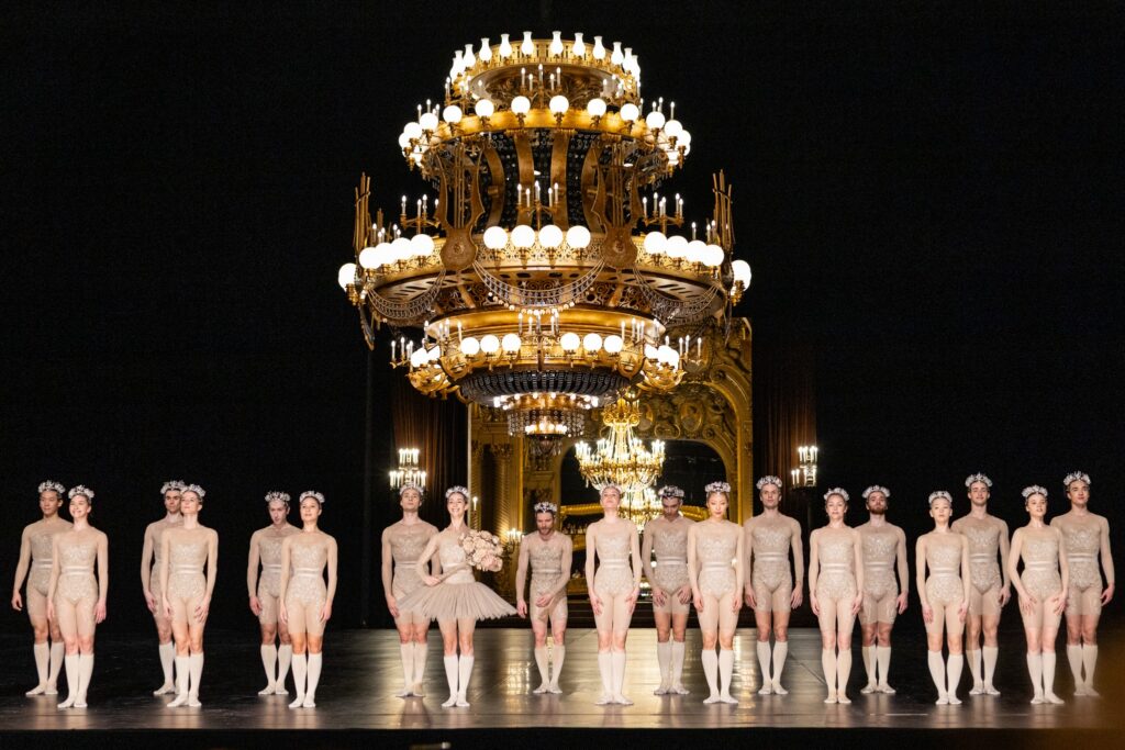 Dancers onstage beneath a grand chandelier in an ornate theater during a summer dance performance.