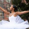 Ballerina in a white tutu posing outdoors for a summer dance festivals feature by Dandelion Chandelier.