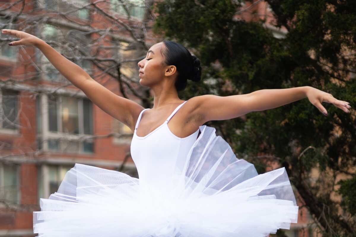 Ballerina in a white tutu posing outdoors for a summer dance festivals feature by Dandelion Chandelier.