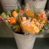 Summer host gift ideas shown through peach and orange flowers in a metal bucket at a flower shop