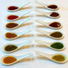Hot sauce tasting flight in white spoons showing red, green, golden and chili crisp sauces for a beginner’s guide to hot sauce.