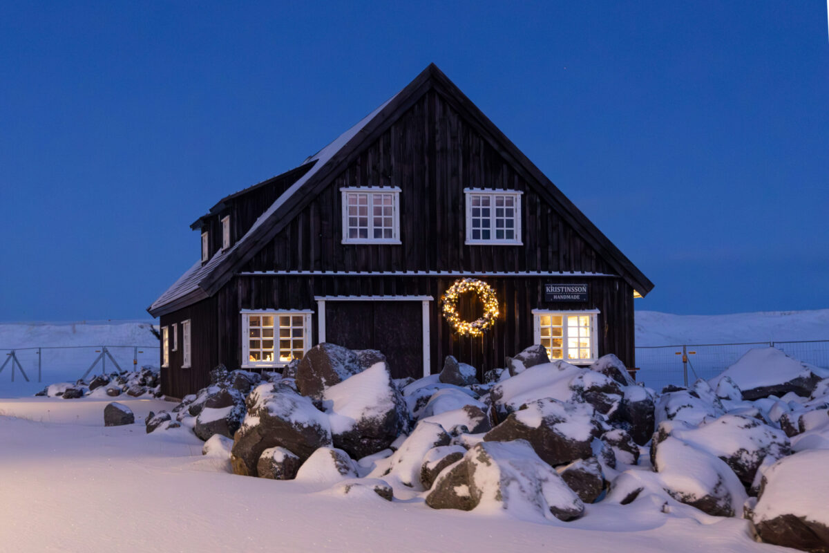 A warmly illuminated Icelandic house at blue hour introducing a luxury gift edit inspired by fifteen twilight colors.