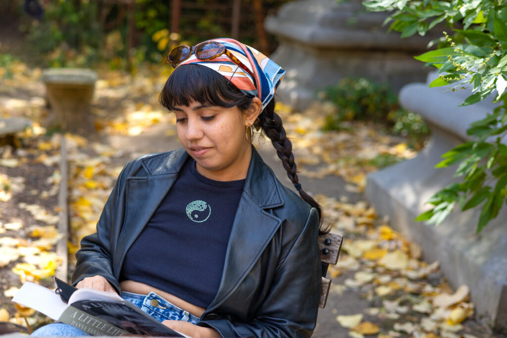 Woman reading a book outdoors among fallen autumn leaves, photographed by Pamela Thomas-Graham for Dandelion Chandelier’s October reading list.