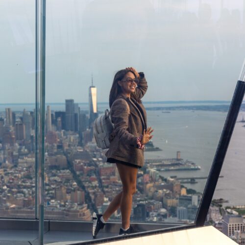 Woman in a checked oversized blazer, sneakers and backpack overlooking New York City, photographed by Pamela Thomas-Graham.