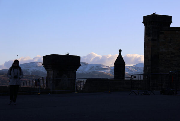 Edinburgh Castle silhouetted above distant snow-covered hills in Scotland, photographed by Pamela Thomas-Graham.