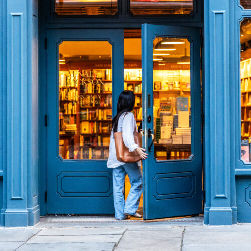 Woman entering a blue independent bookstore at twilight for Dandelion Chandelier’s guide to the best new books of September 2026.