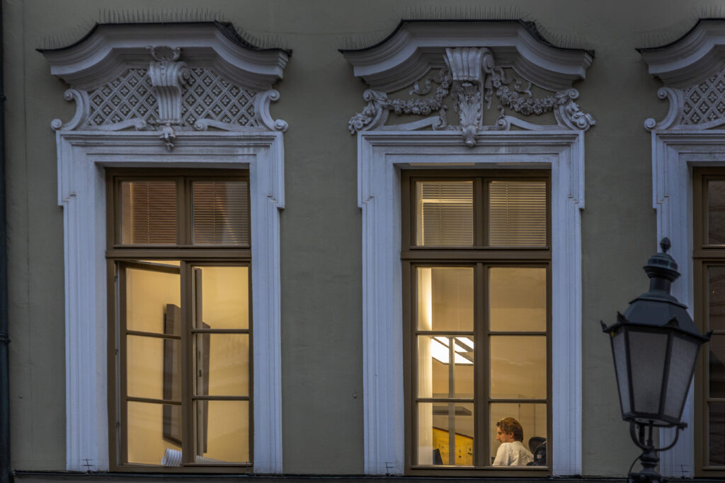 A person working behind a warmly lit office window, illustrating how a small gift from a peer can create welcome and ease at work.