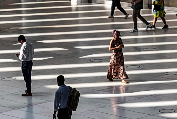 People crossing a sunlit office lobby for a guide to gift etiquette at work, hierarchy, professional judgment, and reading the room.