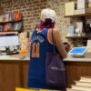 Reader in a Jalen Brunson jersey browsing at the counter of an independent bookstore in New York.