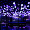 Violet and white glowing spheres above suspended swings in Hyperstudio’s 10 Agosto installation at Balloon Museum NYC.