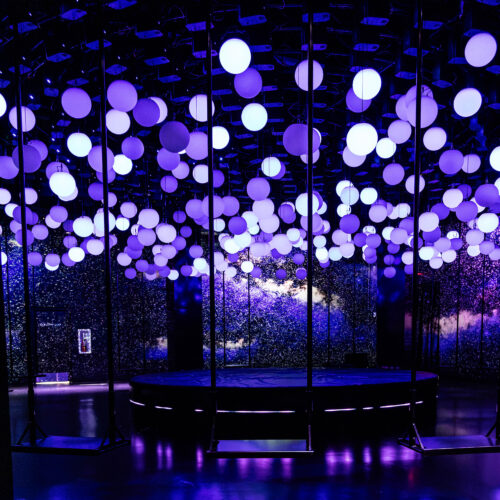 Violet and white glowing spheres above suspended swings in Hyperstudio’s 10 Agosto installation at Balloon Museum NYC.