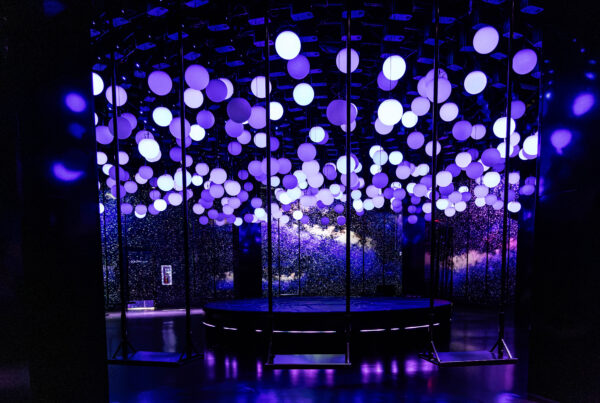 Violet and white glowing spheres above suspended swings in Hyperstudio’s 10 Agosto installation at Balloon Museum NYC.